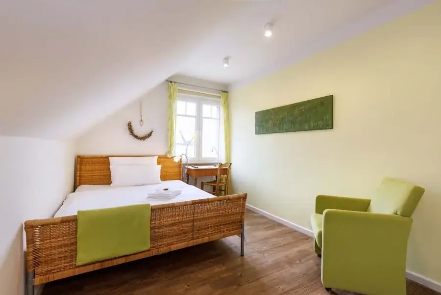 Grünes Einzelzimmer mit Bett und Sessel
